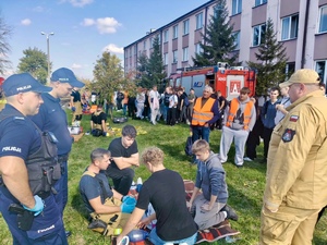 uczniowie ćwiczący resuscytację krążeniowo oddechową oraz umundurowani policjanci