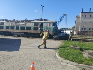 strażak bignący w stronę symulowanego uderzenia pociągu w samochód osobowy