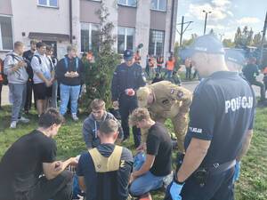 policjanci umundurowani i uczniowie ćwiczący resuscytację krążeniowo oddechową