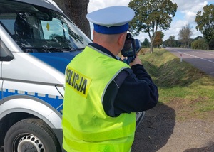 policjant ruchu drogowego przy radiowozie i ciągnik w tle