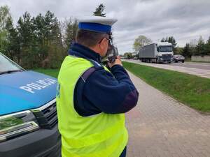 policjant przy radiowozie mierzy prędkość