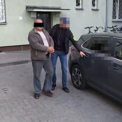 policjant prowadzi zatrzymanego