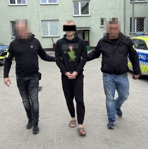 policjanci prowadzą zatrzymanego mężczyznę