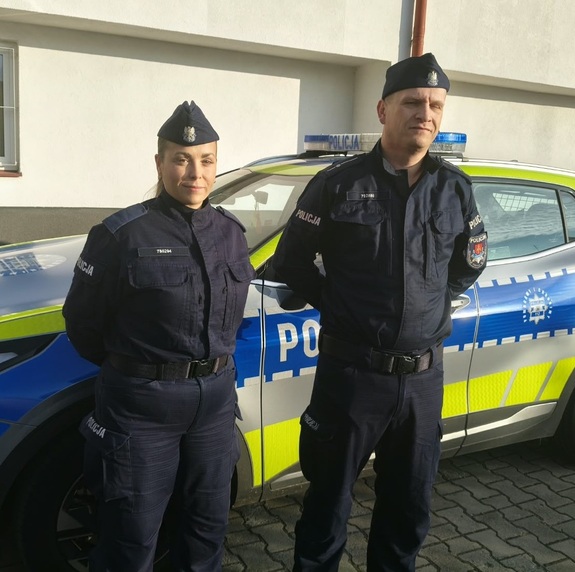 policjanci stoją przy radiowozie