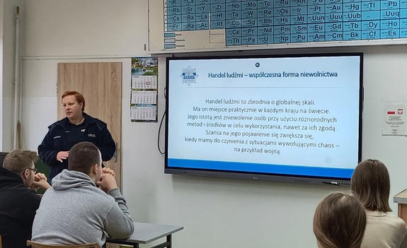 policjantka stoi przy tablicy podczas spotkania z młodzieżą