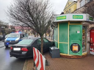 miejsce zdarzenia, samochód rozbity o kiosk i radiowóz w tle