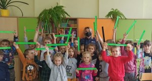 policjantka podczas grupowego spotkania z uczniami trzymającymi opaski odblaskowe