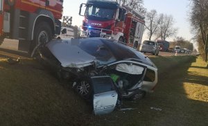 rozbity pojazd osobowy, w tle pojazdy straży pożarnej