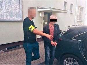 zatrzymany mężczyzna w kajdankach obok policjant