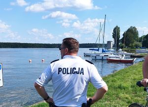 policjant patrzy na wodę w zalewie