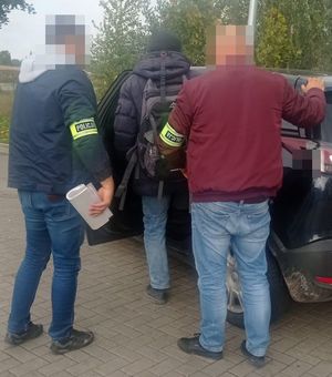 policjanci doprowadzają zatrzymanego