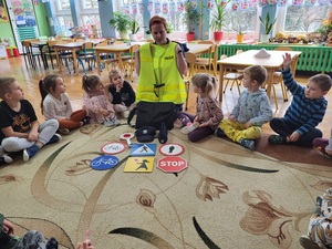 policjantka pokazuje dzieciom kamizelkę odblaskową