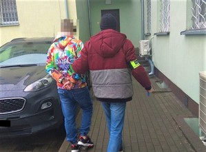 policjant doprowadza zatrzymanego do budynku policji