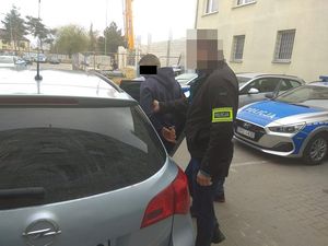 policjanci doprowadzają zatrzymanego