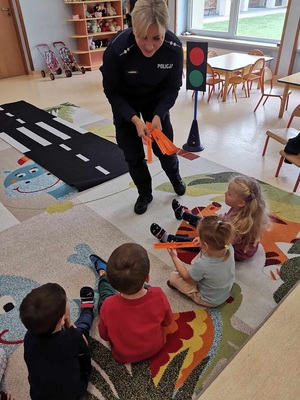 policjantka ćwiczy z dziećmi przechodzenie przez przejście dla pieszych