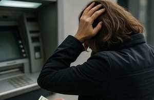 kobieta stojąca przed bankomatem